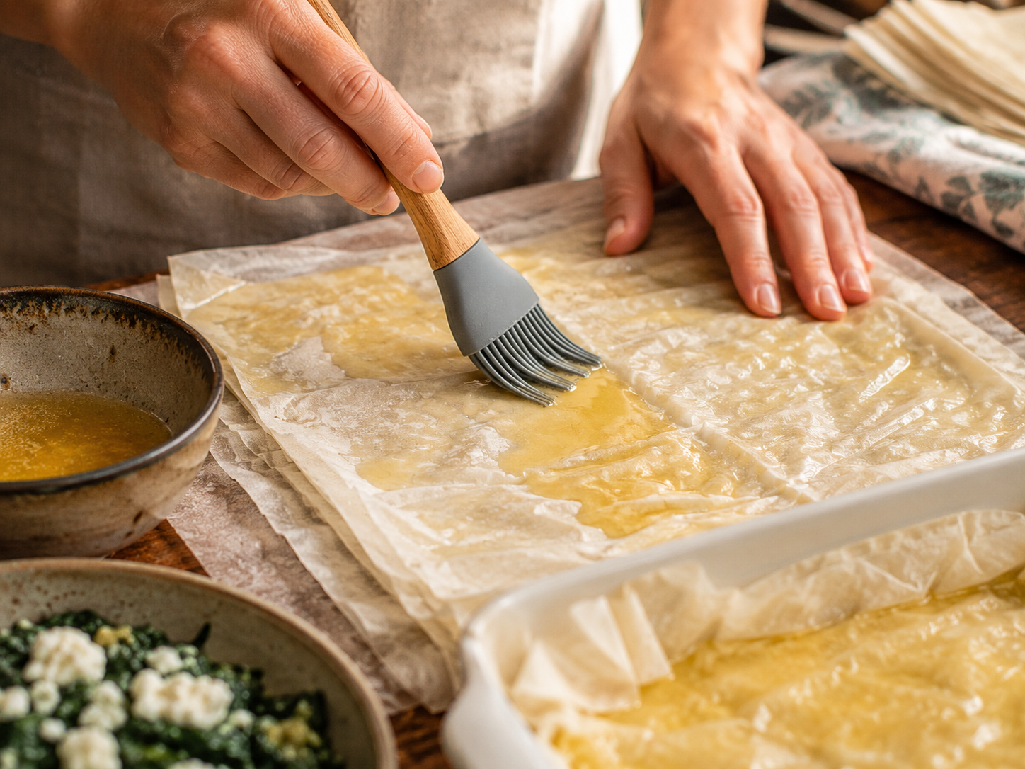 mains qui badigeonnent beurre fondu feuille filo spanakopita grecque