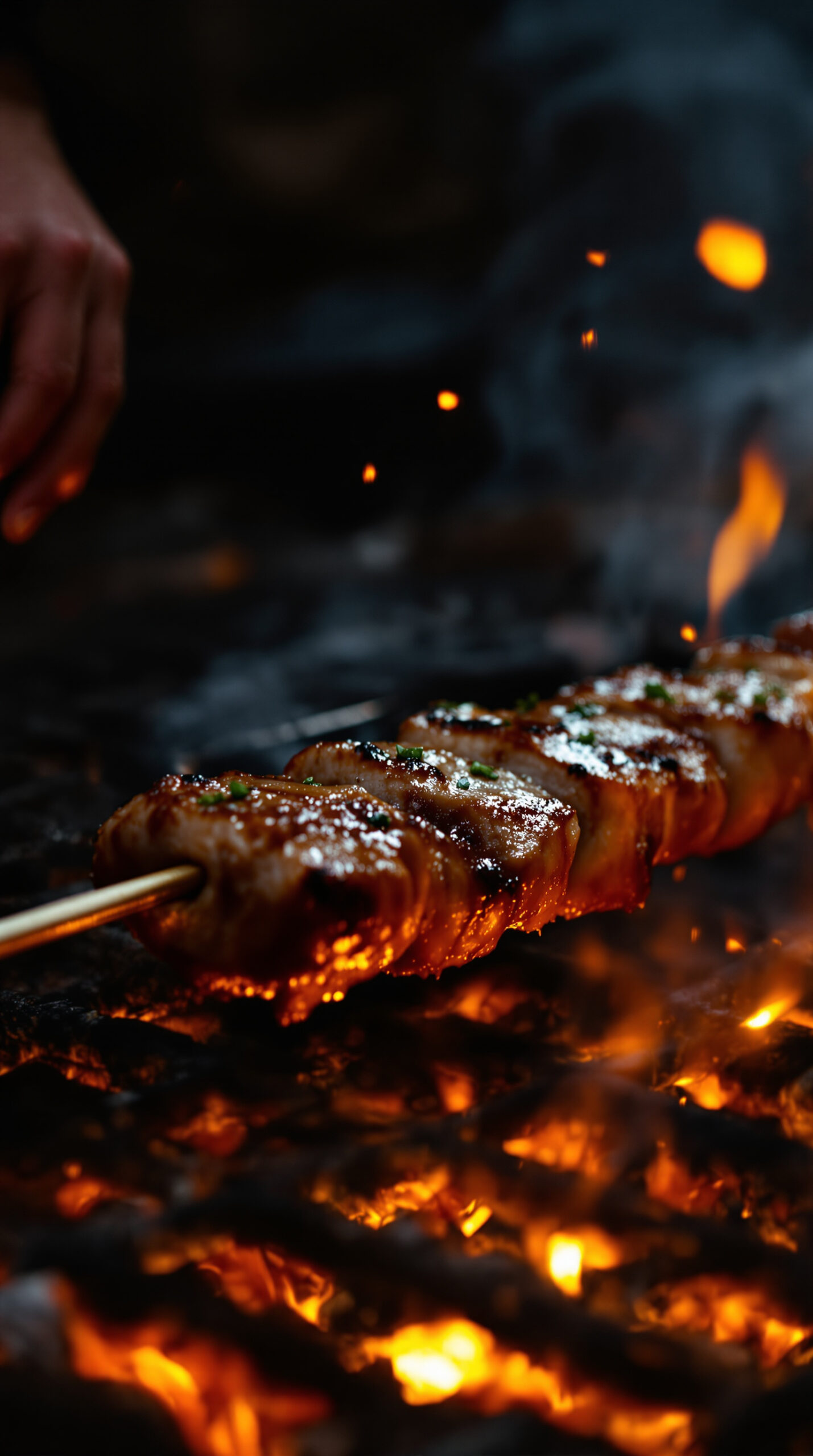 Main retournant une brochette de viande marinée au-dessus de braises rougeoyantes