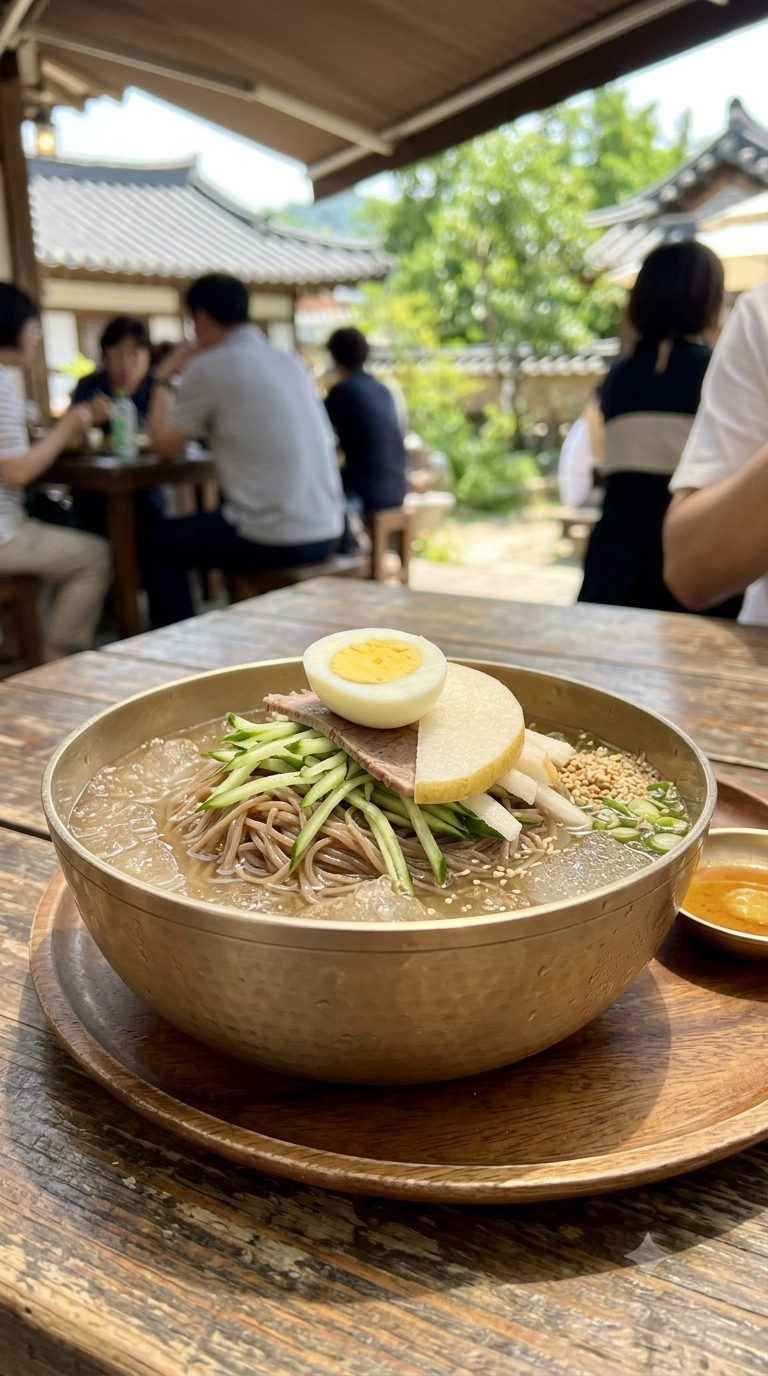 Bol en métal traditionnel coréen rempli de naengmyeon glacé, nouilles fines de sarrasin, concombre, poire et œuf dur