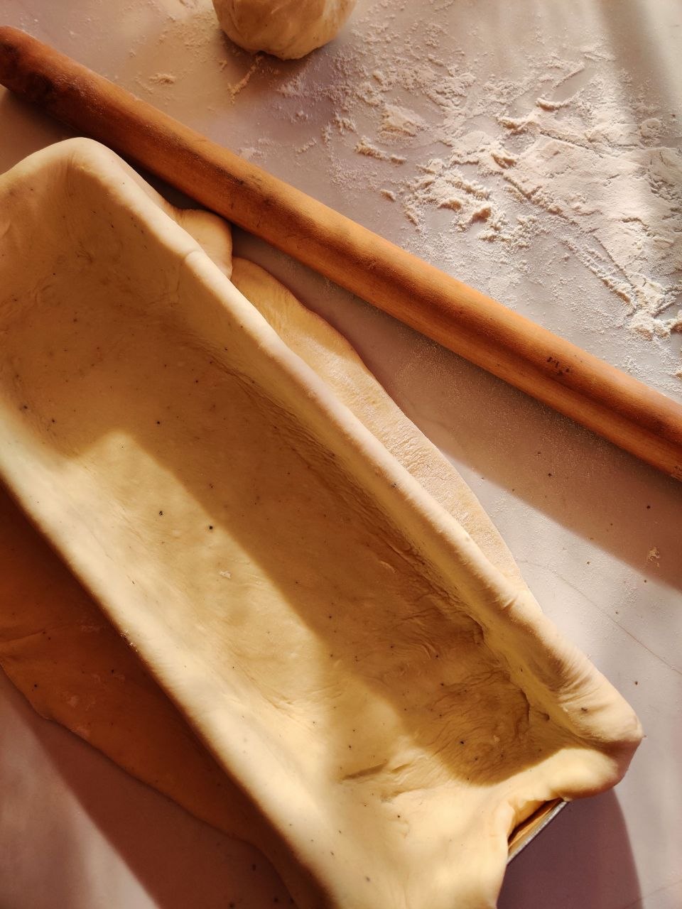 Mains roulant une fine pâte levée autour d'une garniture de noix hachées