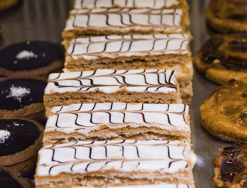 Mille-feuille coupé en tranche, couches de pâte feuilletée et de crème pâtissière bien visibles, sur un plateau ancien en argent