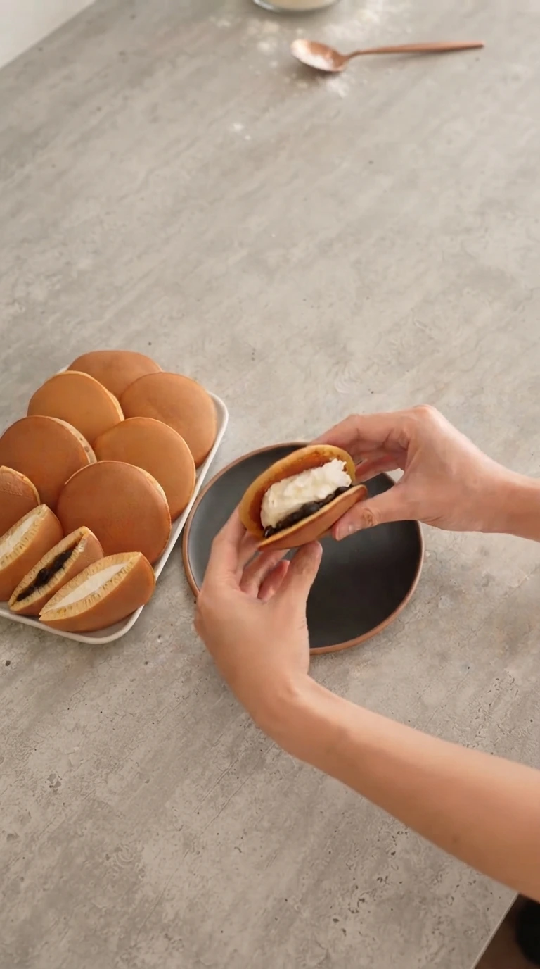 Mains versant la pâte à la louche sur une plaque chaude pour former les disques du dorayaki