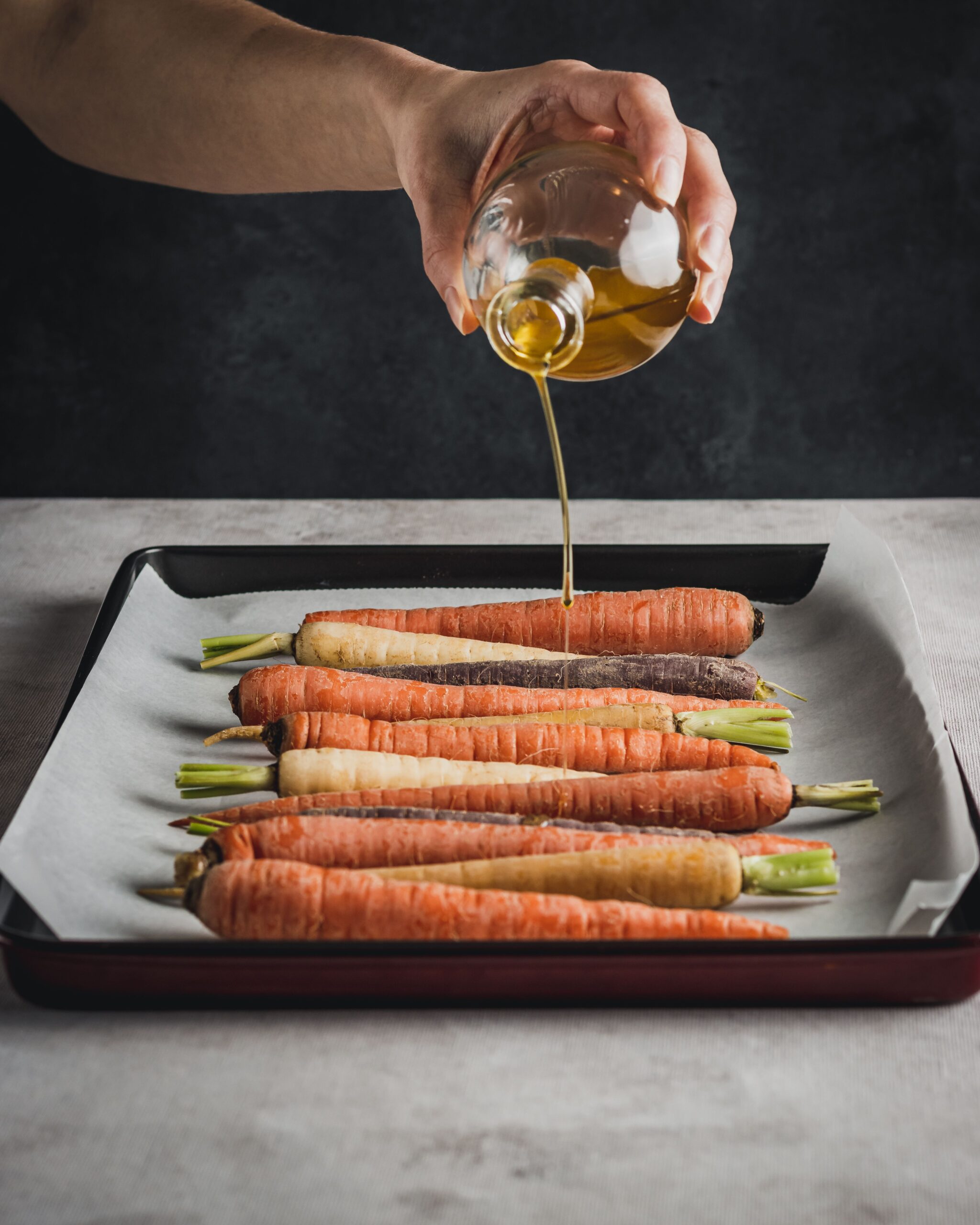 Mains disposant des carottes entières sur une plaque avant enfournage