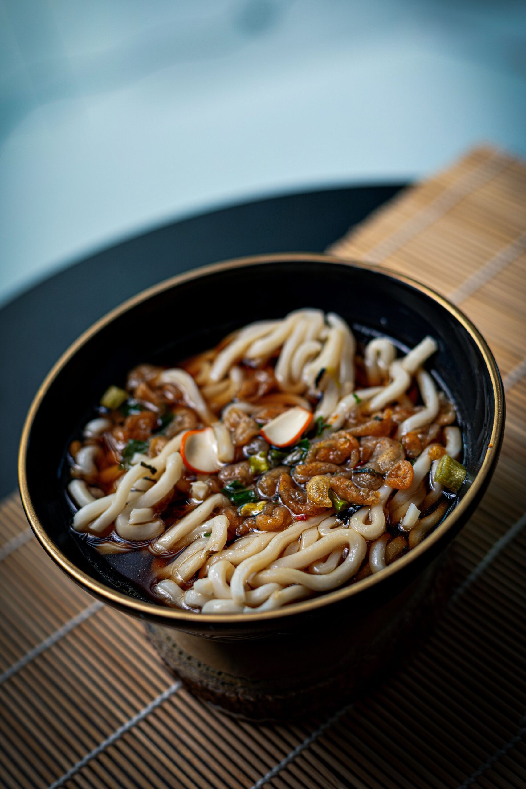Bol en céramique japonaise sombre rempli de soupe udon, nouilles épaisses dans un bouillon clair