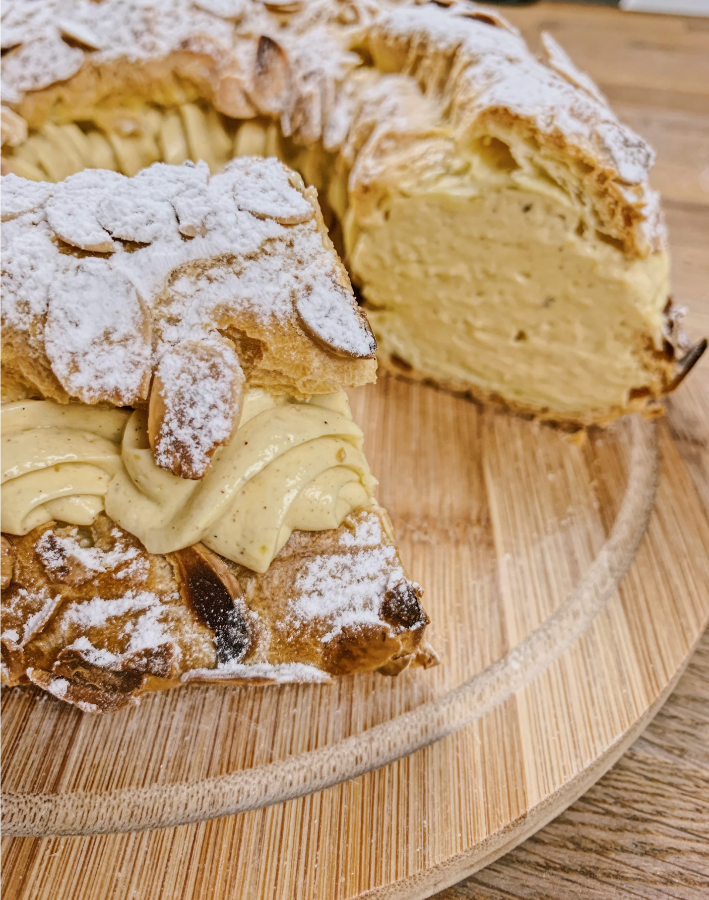Paris-brest tranché révélant une couche de crème pralinée et amandes effilées
